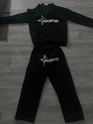 Svart NOFS tracksuit set - Svart tracksuit set från NOFS med matchande tröja och byxor. Båda plaggen har en stor vit NOFS-logga med stjärndesign framtill. Byxorna har resår i midjan och sidofickor. Perfekt för chill dagar hemma. Storlek M men passar även S. 250 per piece eller 400 för setet