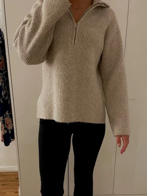 Stickad halvzip tröja - Mysig beige stickad tröja med halvzip och krage. Tröjan har en rak passform, långa ärmar och ribbstickad struktur. Perfekt för lager på lager och enkel att styla till olika outfits. ❣️