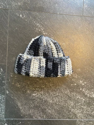 Handgjord virkad mössa  - Handgjord virkad mössa i ull. Vit grå och svart melerad. Aldrig använt 