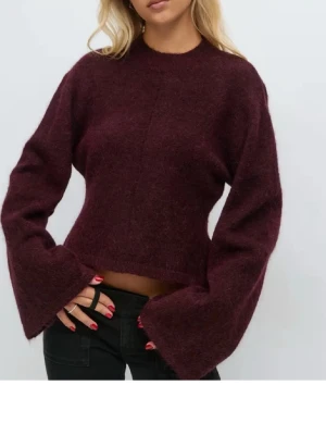 Vinröd stickad tröja - Vinröd stickad tröja med figurad passform och vida ärmar. Tröjan har rund halsringning och är tillverkad i ett mjukt, fluffigt material som ger en mysig känsla. Den är i nyskick utan prislapp.