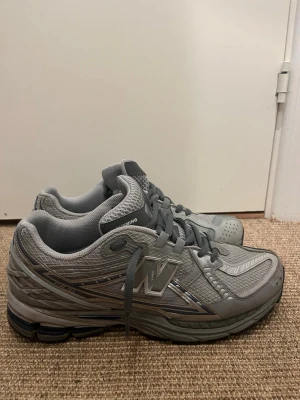 Grå New Balance sneakers - Snygga grå sneakers från New Balance med mesh- och syntetmaterial. Skorna har klassisk siluett, reflekterande detaljer och snörning. Perfekta för dig som gillar sportig stil och vill ha bekväma skor till vardags. NB-logga på sidan och ventilerande ovandel. PRISET KAN DISKUTERAS VID SNABB AFFÄR TVEKA INTE PÅ ATT HÖRA AV ER