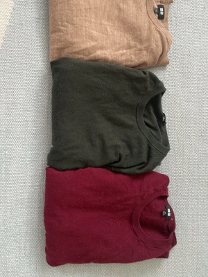 3-pack basic tröjor från Uniqlo - Säljer ett 3-pack basic tröjor från Uniqlo i färgerna beige, mörkgrön och vinröd. Alla har rund halsringning och är tillverkade i mjukt bomullsmaterial. Går att köpa enskilt. 