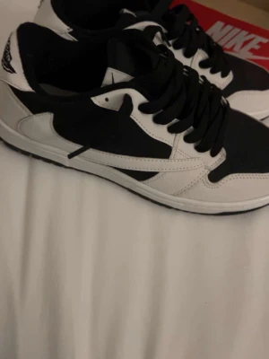 Nike svartvita sneakers - Svartvita Nike sneakers med klassisk Swoosh-logga på sidan. Skorna har lågt skaft, svarta skosnören och en vit sula. Ovandelen är i en mix av svart och vitt läder, vilket ger en stilren och sportig look. Perfekta för dig som gillar streetwear och enkel stil.