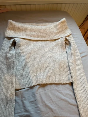  off shoulder stickad tröja - Trendig stickad tröja från H&M med bred off shoulder-krage och ribbad struktur. Perfekt för dig som gillar en avslappnad men ändå snygg stil. Långa ärmar och mjukt material som känns skönt mot huden.