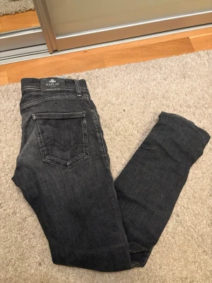 Replay jeans - Snygga svarta jeans från Replay med smal passform och klassisk femficksdesign. Jeansen har diskreta slitningar och är tillverkade i stretchigt denim för en bekväm känsla. Perfekta för dig som gillar en stilren och modern look.