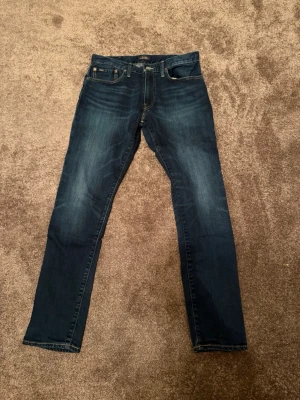 Mörkblå jeans från Polo Ralph Lauren - Snygga mörkblå jeans från Polo Ralph Lauren med klassisk femficksdesign och raka ben. Jeansen har subtila slitningar och en liten logga på bakfickan. Perfekta till vardags för en avslappnad men stilren look. Storlek 31/32