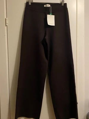 Bruna vida byxor från MSCH Copenhagen - nya med prislappar  - Byxorna har en rak skärning, med normal midja och resår i midjan.  Storlek S/M   Amalea Hasle Byxor Den rätta färgen är där byxorna är mörkare  Dessa byxor har en normal passform.  70 % LENZING™ ECOVERO™ viskosfibrer och 30 % återvunnen polyester Innerbenslängd 77 cm  Bred 29 cm ( rakt över byxben) 