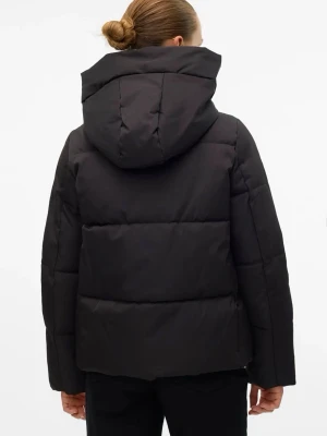 Svart pufferjacka med huva - Säljer en svart pufferjacka med stor, mysig huva och breda quiltade paneler. Jackan har rak passform och dold dragkedja framtill. Perfekt för kalla vinterdagar och ger en stilren look.