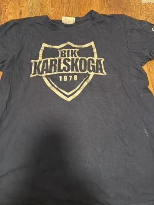 BIK Karlskoga t-shirt från Clique - Mörkblå t-shirt från Clique med stort BIK Karlskoga-tryck på bröstet och årtalet 1978. Klassisk passform med korta ärmar och rund hals. Perfekt för dig som vill visa ditt stöd för laget.
