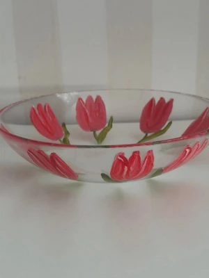 Glasskål med röda tulpaner Ulrika Hydman Valien - En glasskål dekorerad med röda tulpaner från Kosta Boda. Skålen har en klar design med målade tulpanmotiv runt om, signerat.Diameter 19 cm, höjd 5 cm. 
