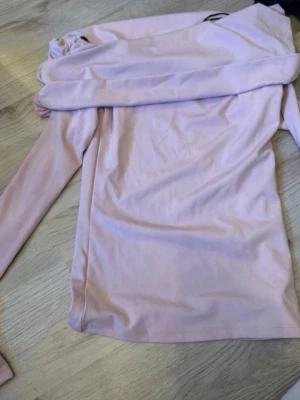 Ljusrosa långärmad topp - Säljer en enkel och stilren ljusrosa långärmad topp i mjukt material. Perfekt att matcha med jeans eller kjol för en clean look. Toppen har en rak passform och är superbekväm att bära.