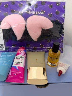 Skönhetspaket med hårband och hudvård - Ett skönhetspaket med ett rosa och svart fluffigt hårband, Clarins Hydra-Essentiel ansiktskräm, Yves Rocher Awaken Glow Scrub, Canopy hudkräm, Pure Skin Dream Oil och en liten tub ögonkräm. Perfekt för dig som vill testa olika hudvårdsprodukter.
