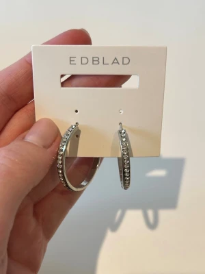 Stora silvriga hoops - Snygga stora hoops i silverfärgad metall med glittrande stenar längs hela framsidan. Perfekta för dig som vill ha ett statement-smycke som verkligen syns. Klassisk rund form och stilren design. De är i använt skick därav priset!🙏🏻