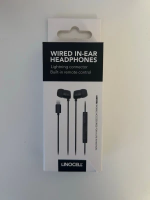 Linocell svarta in-ear hörlurar - Ett par svarta in-ear hörlurar från Linocell med lightning-kontakt, perfekt för iPhone, iPad och iPod. Hörlurarna har inbyggd mikrofon och fjärrkontroll för att justera volym och ta samtal. Kabeln är 122 cm lång. Aldrig använda.