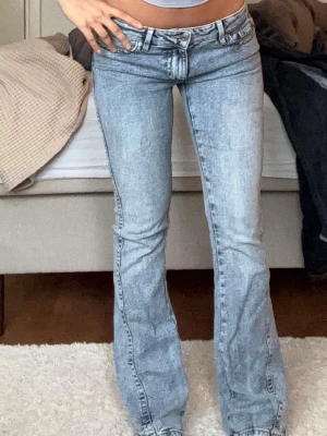 Ljusblå bootcut jeans med detaljer - Säljer ett par ljusblå bootcut jeans med snygg tvätt och snygga bakfickor. låg midja och är tillverkade i stretchig denim för skön passform. Perfekta för dig som gillar en vintage lowwaist look.