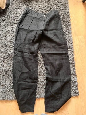 Svarta byxor med avslappnad passform - Säljer ett par svarta byxor med avslappnad och loose passform. Byxorna har hög midja, raka ben och sidofickor. Perfekta för varma dagar och enkel att matcha med olika toppar.