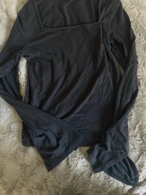 Svart långärmad topp XOXO by Brands - En svart långärmad topp från XOXO by Brands med enkel och stilren design. Toppen har en rak passform och är tillverkad i mjukt material som känns skönt mot huden. Perfekt att matcha med jeans eller kjol för en clean look.