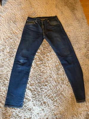 Mörkblå skinny jeans från Levi's - Säljer ett par mörkblå skinny jeans från Levi's med klassiska fem fickor och snygga kontrastsömmar. Jeansen har en smal passform och är tillverkade i stretchigt denim för extra komfort. Perfekta till en avslappnad streetstyle-look.