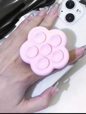 1 sugpropp  - Säljer en söt rosa pop it mobilhållare i form av en blomma. Perfekt att fästa på baksidan av mobilen för bättre grepp och som stressleksak. Tillverkad i mjuk silikon som är skön att hålla i och enkel att använda.