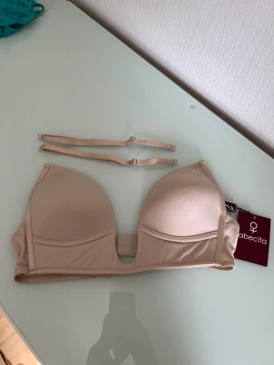 Beige push-up bh från Abecita - Säljer en beige push-up bh från Abecita, modell Amelia Party-push i färgen honey. Bh:n har avtagbara axelband och vadderade kupor för extra lyft. Perfekt under ljusa plagg tack vare den neutrala färgen. Materialet är mjukt och följsamt.