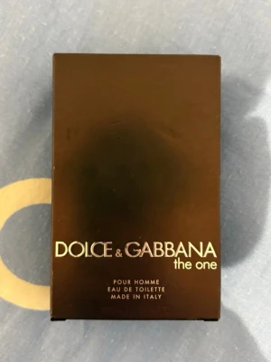 Dolce & Gabbana The One Pour Homme - Dolce & Gabbana The One Pour Homme Eau de Toilette i en elegant svart kartong med stilren logga. Parfymen är tillverkad i Italien och har en lyxig känsla med maskulin design. Perfekt för dig som gillar exklusiva dofter och snygg förpackning.I ml  100!