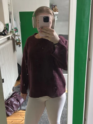 Mörkröd stickad tröja - Mysig stickad tröja i mörkröd färg med rund halsringning och långa ärmar. Tröjan har en enkel, rak passform och är perfekt för lager på lager. Materialet ser mjukt och fluffigt ut, vilket ger en avslappnad vibe. Aldrig använd 