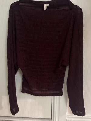 Vinröd topp - Säljer en mörkröd mesh topp med lång ärm och lätt transparent material. Toppen har en loose passform och är perfekt för att styla lager på lager. Enkel och stilren design utan synliga detaljer.