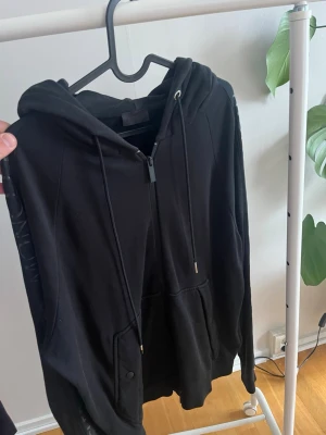  Moncler hoodie - Snygg svart hoodie från Moncler med dragkedja framtill, justerbar huva med snören och fickor på magen. Tillverkad i mjukt material. Perfekt för en avslappnad och trendig look.