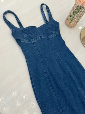 Bershka Blå jeansklänning med smala axelband - Snygg blå jeansklänning med smala axelband och figurnära passform. Säljer eftersom den är för liten, passar XXS, 32 bäst 