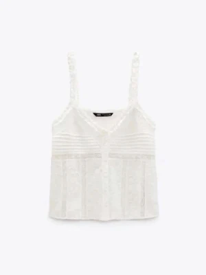 Vit spetslinnetopp från Zara - Säljer en söt vit linnetopp från Zara med spetsdetaljer och knappar framtill. Toppen har tunna axelband och v-ringad halsringning, samt dekorativa sömmar och inslag av spets som ger en romantisk vibe.