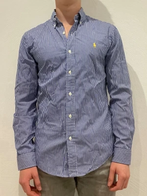 Randig blå skjorta från Ralph Lauren - Ralph Lauren skjorta || Storlek S (slim fit) || Skjortan är i bra skick || Modellen på bilden är 170cm och väger 62kg || Tveka inte på att höra av dig vid frågor eller funderingar 