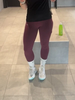 Vinröda leggings från ICANIWILL - Säljer ett par vinröda leggings från ICIW med hög midja och tight passform. Perfekta för träning eller chill, tillverkade i stretchigt material som sitter skönt mot kroppen. Diskret logga vid höften och klassisk design.