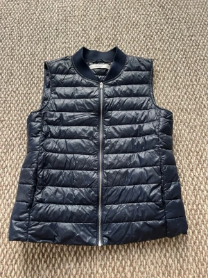 Mörkblå dunväst från Mango - Mörkblå dunväst från Mango med quiltad design och dragkedja framtill. Västen har en ribbad krage och är lätt vadderad för extra värme. 