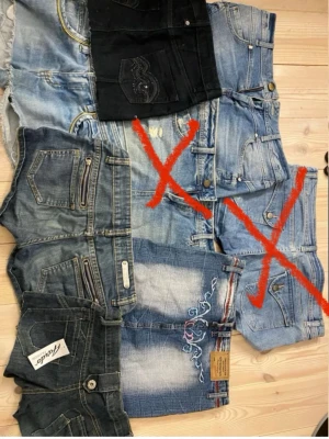 Mix av jeansshorts och svarta shorts - Säljer ett gäng olika jeansshorts i blå denim och ett par svarta shorts med broderade bakfickor. Flera av shortsen har slitna detaljer, dragkedjor eller broderier. Perfekta för sommaren och passar till det mesta. Alla är klassiska femficksmodeller.! ALLA SÄLJS FÖR SIG! 