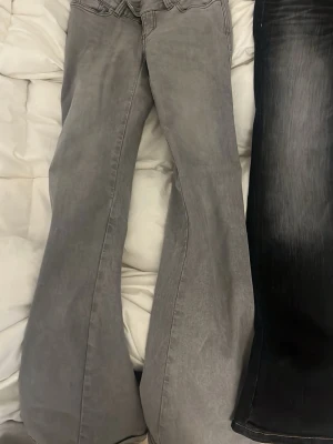 lågmidjade gråa bootcut jeans med brodyr - Säljer ett par gråa bootcut jeans med snygg brodyr på bakfickorna. Jeansen har utsvängda ben och klassisk femficksmodell. 