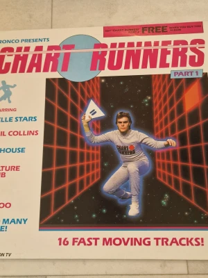 Ronco Chart Runners Part 1 vinylskiva samlingsalbum - Ronco Chart Runners Part 1 vinylskiva samlingsalbum.  LP:n är ett samlingsalbum med 16 låtar av olika artister. Omslaget visar att medverkande artister inkluderar bland annat Belle Stars, Phil Collins, Icehouse, Culture Club, U2, Yazoo och flera andra. Baksidan listar låtarna uppdelade på två sidor (Side One och Side Two) med respektive artist.