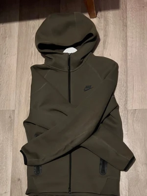 Olivgrön Nike tech hoodie med dragkedja - Säljer denna olivgröna nike tech hoodie i storlek S. Använt fåtal gånger så inga problem på den