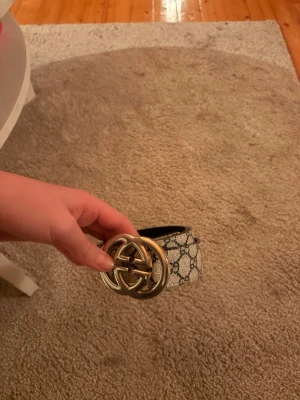 beige bälte med GG-spänne - Snyggt beige bälte  med klassiskt GG-mönster och stort guldfärgat GG-spänne. Bältet har en exklusiv känsla och passar perfekt till jeans eller byxor för att lyfta din outfit.bra skick 