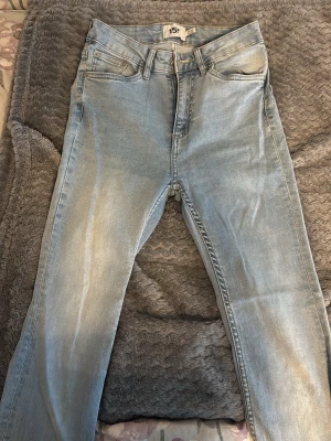 High Waist Bootcut Jeans  - Säljer ett par ljusblå jeans från lager 157  med klassisk femficksmodell och bootcut. Jeansen har hög midja och subtila slitningar framtill för en avslappnad look. Perfekta till en casual outfit och passar till det mesta. Aldrig använda 