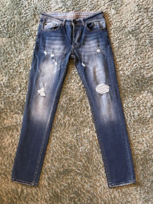 Jeans med slitningar - Säljer ett par slim jeans med slitningar från Troy king, Jeansen är i storlek 30/30. Aldrig använda. Skriv vid intresse!
