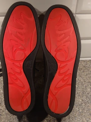 Svarta sneakers med röd sula - Snygga svarta sneakers med ovandel i mocka och klassisk snörning. Skorna har en unik röd yttersula som sticker ut och ger en cool kontrast. Perfekta för dig som vill ha en stilren men ändå lite edgy look. Passar till det mesta i garderoben.