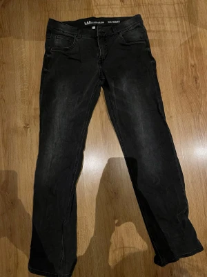 Svarta jeans från LAB Industries - Snygga svarta jeans från LAB Industries med klassisk femficksmodell och raka ben. Jeansen har diskreta slitningar och är tillverkade i ett mjukt denimtyg som ger en skön känsla. Perfekta för dig som gillar en stilren och enkel look.