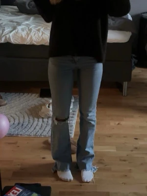 Ljusblå bootcut jeans med slitning - Säljer dessa trändiga ljusblå bootcut jeans med slitning vid knät . Med en medelhög midja i storlek 32 från Gina Tricot💕😊.