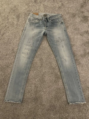 Dondup George W30 - Säljer ett par ljusblå jeans med slitningar och råa kanter vid bensluten. Jeansen är skinny fit och har smal och rak passform. Tillverkade i denim med snygg tvättad look. Hör av dig vid minsta lilla fundering, eller prisförslag.