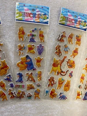 Nalle Puh klistermärken set - Säljer ett set med färgglada Nalle Puh klistermärken med motiv av Puh, Tiger, Ior och Nasse. Perfekta för att dekorera anteckningsböcker, mobilskal eller brev. Klistermärkena har olika former och storlekar och är gjorda av plast med glansig yta.