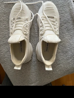Vita Steve Madden sneakers - Snygga vita sneakers från Steve Madden med chunky sula . Skorna har vita snören, tydlig logga på sidan och bak, samt en sportig design som ger en modern vibe. Perfekta för dig som gillar streetstyle och vill ha något bekvämt och trendigt.  Storlek 38