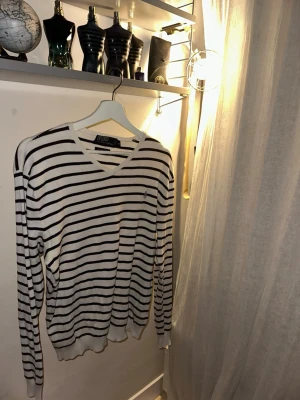 Randig stickad tröja från Polo Ralph Lauren - Säljer en vit stickad tröja med svarta horisontella ränder från Polo Ralph Lauren. Tröjan har V-ringning, långa ärmar och en liten broderad logga på bröstet. Perfekt för en stilren och avslappnad look. Priset är inte hugget sten     Storlek : Medium   