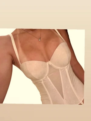 Vit spetskorsett med avtagbara band - Säljer en elegant vit korsett topp med tunna axelband och avtagbara strumpeban🫶🏻😊. Korsetten har vadderade kupor, diskret blommönster och meshdetaljer som ger en snygg siluett 🌸 Den har en dragkedja på sidan och är mer en korsett topp den är alltså inte snatching men sitter jättefint ändå🥰 Kuporna är för små för mig med C kupor men en B kupa är nog mer passande 