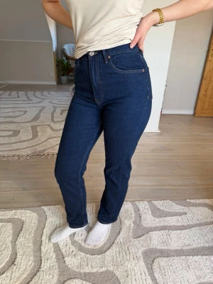 Mörkblå raka jeans med hög midja - Snygga mörkblå jeans med rak passform och hög midja. Klassisk femficksmodell med kontrastsömmar och knappgylf. De är från Gina Tricot. Använda ett fåtal gånger 