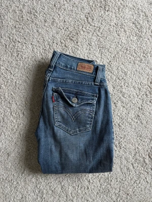 Levis jeans - Säljer ett par snygga blå bootcut/flare jeans i klassisk modell! De sitter superfint på kroppen och ger en smickrande passform över höfter och ben. Perfekta till både vardag och fest – matcha med sneakers, boots eller klackar.  Jeansen är i fint skick dock med ett litet litet hål vid bakfickan (där av priset) men går att sys igen enkelt och har en riktigt snygg tvätt som passar till allt. Trendiga men samtidigt tidlösa! 